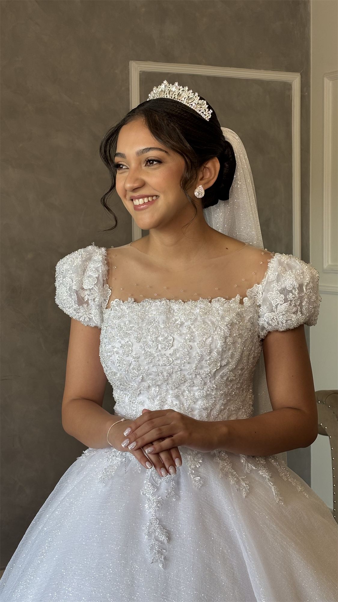 Noiva de tiara e vestido de renda sorrindo de mãos dadas