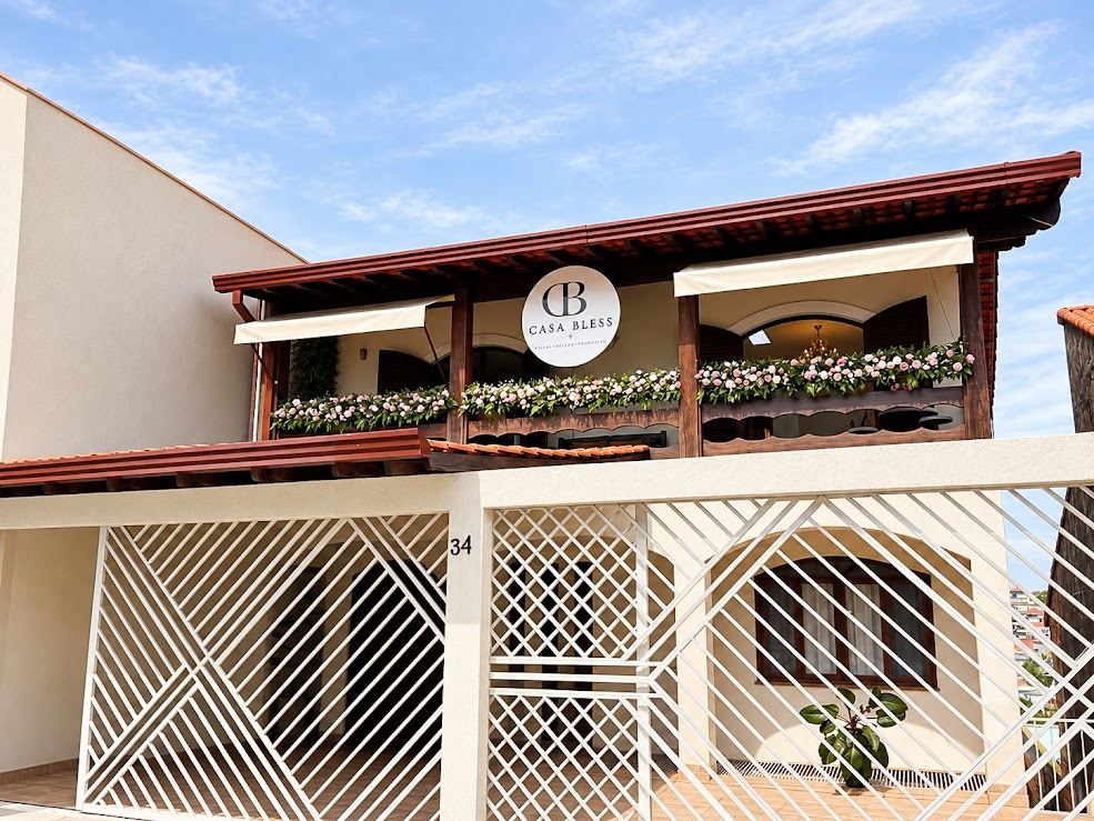 Fachada da Casa Bless, com o letreiro na varanda decorada com flores