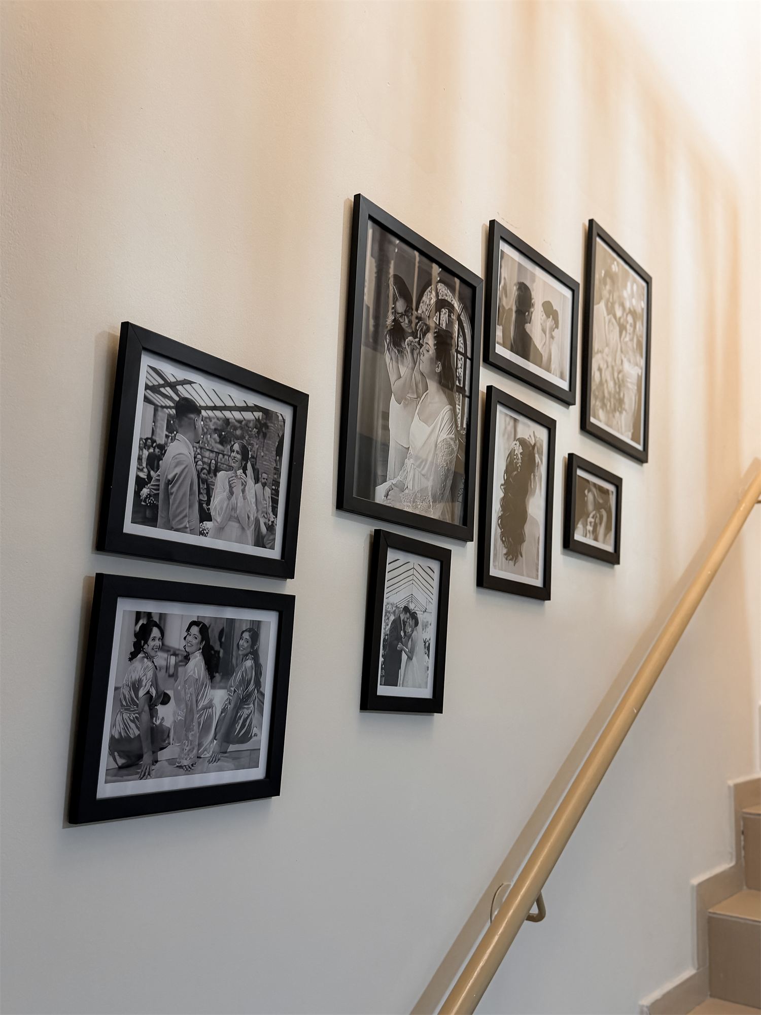 Parede da escada com fotografias de noivas em preto e branco em molduras pretas