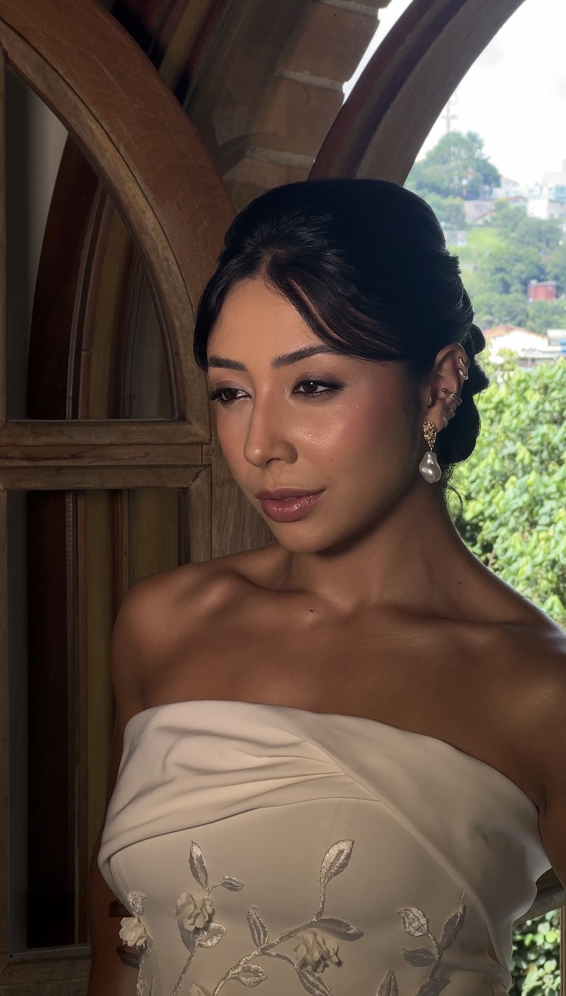 Noiva de vestido tomara que caia diante de uma janela de madeira em arco